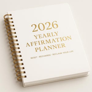 May include: A white spiral-bound planner with gold lettering that reads "2026 YEARLY AFFIRMATION PLANNER." The planner also has the words "RESET • RECHARGE • RECLAIM YOUR LIFE" printed on the cover. The spiral binding is gold.