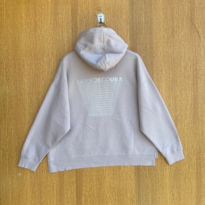 May include: A light gray hoodie with a large graphic on the back that says "DR SHOE CO USA" repeated in a pattern.