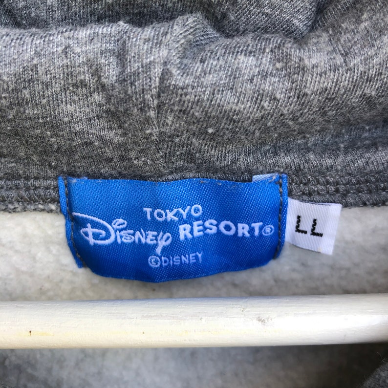May include: A blue label with white text that reads "Tokyo Disney Resort" and "&copy;Disney". The label also has a size tag that reads "LL".