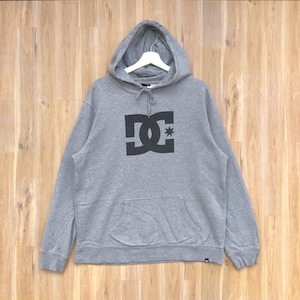 May include: Gray hooded sweatshirt with a black DC logo and a small star above the C. The sweatshirt has a kangaroo pocket.