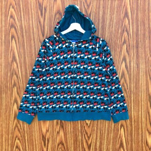 May include: Teal zip-up hoodie with a repeating pattern of Mickey Mouse faces in red, black, and white. The hoodie features a matching teal hood, cuffs, and waistband, and a full-length zipper.