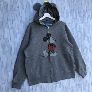 May include: A gray zip-up hoodie with a vintage Mickey Mouse graphic on the front. The hoodie has a hood with attached ears.
