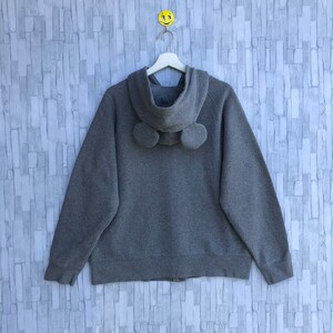 May include: A gray zip-up hoodie with a hood and two fuzzy ear-like details on the back.