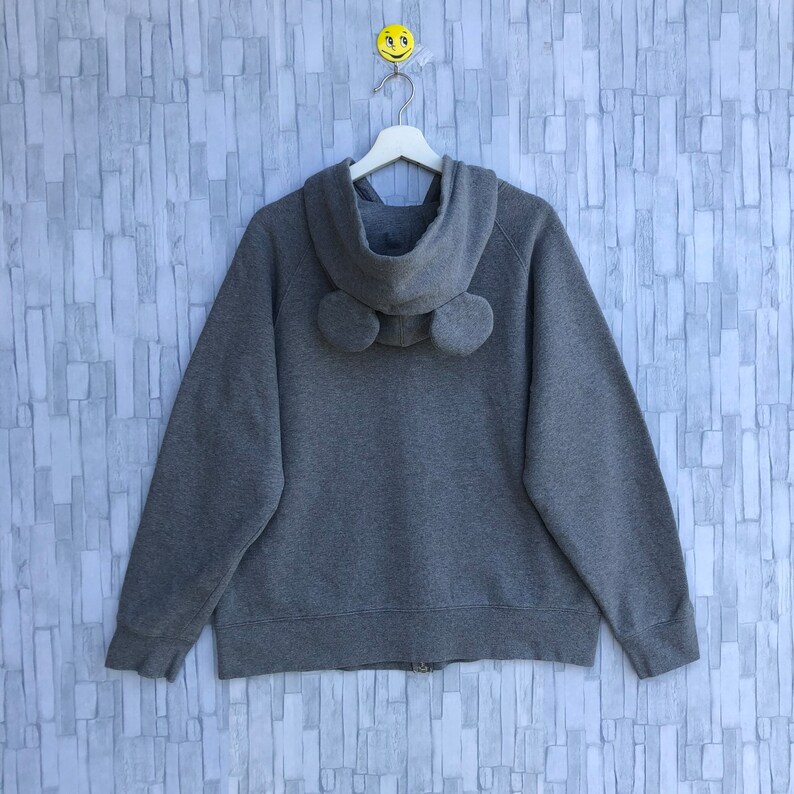 May include: A gray zip-up hoodie with a hood and two fuzzy ear-like details on the back.