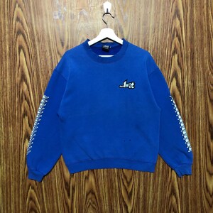 May include: A royal blue sweatshirt with the word "...lost" in white and black on the chest. The sleeves have a white and black design. The sweatshirt is hanging on a white hanger against a wooden background.