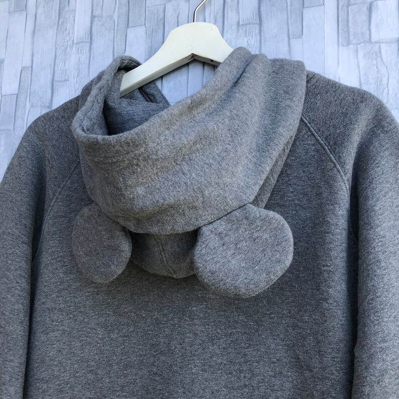 May include: Gray hooded sweatshirt with a large hood and two fabric ear-like details on the back.
