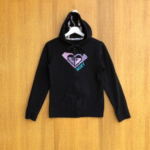 May include: Black zip-up hoodie featuring a Roxy logo. The logo is a heart-shaped design with a zebra print and the word "ROXY" in teal. The hoodie has a drawstring hood and a front pocket.