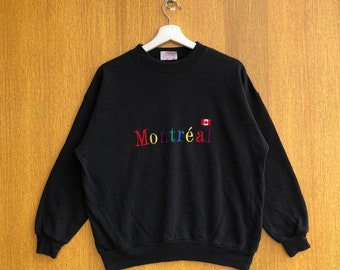 May include: Black long-sleeve sweatshirt with a rainbow embroidered "Montréal" text and a small Canadian flag.