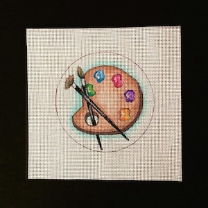 May include: A brown wooden artist's palette with colorful paint swatches and two paintbrushes crossed on top.