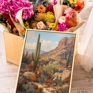 May include: A framed painting of a desert landscape with tall cacti and rocky hills. The painting is in a gold frame and is sitting on a wooden floor. The painting is titled "Ready to print ROMA Romantic and Vintage Art".