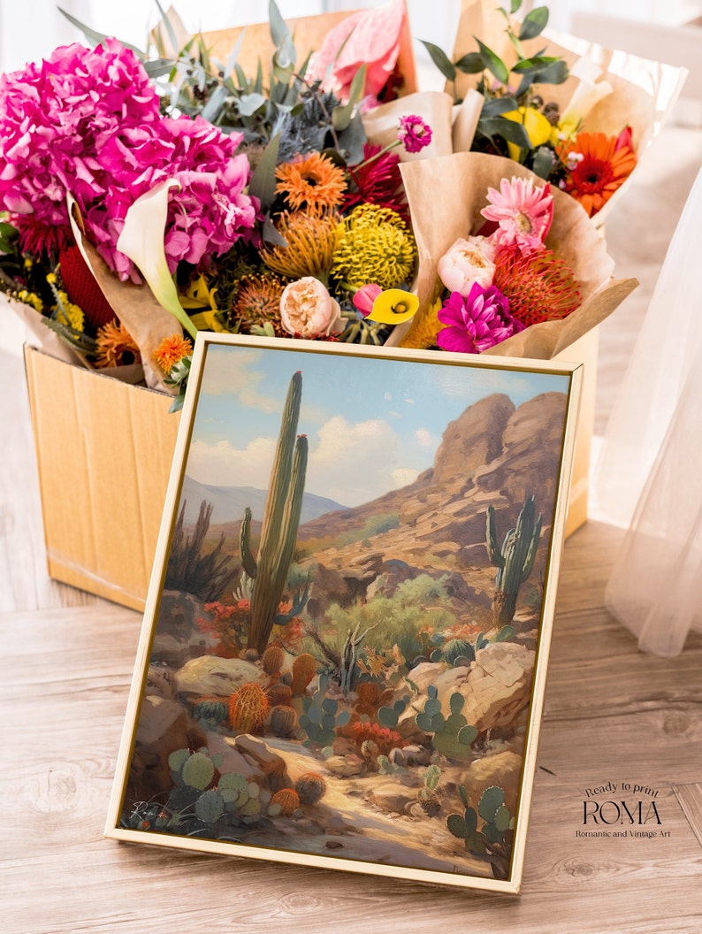 May include: A framed painting of a desert landscape with tall cacti and rocky hills. The painting is in a gold frame and is sitting on a wooden floor. The painting is titled "Ready to print ROMA Romantic and Vintage Art".