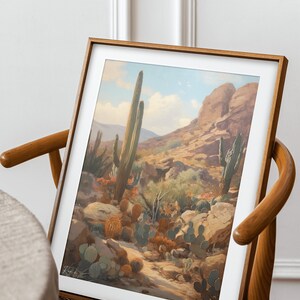 May include: A framed print of a desert landscape with tall cacti and smaller cacti in the foreground. The print is in a wooden frame and is hanging on a wall.