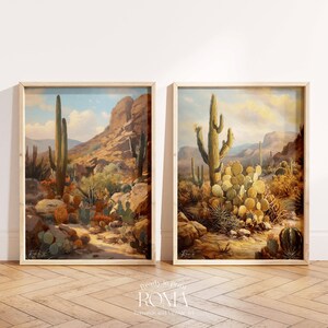 May include: Two framed paintings of desert landscapes with cacti and mountains. The paintings are in a light wood frame and are hanging on a white wall.