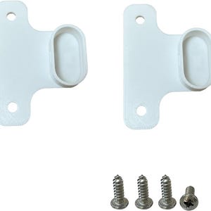 Può includere: Due staffe bianche stampate in 3D, ciascuna con un supporto ovale e due fori per le viti. Quattro viti argentate sono posizionate sotto. Le staffe sono probabilmente per il montaggio o il supporto.