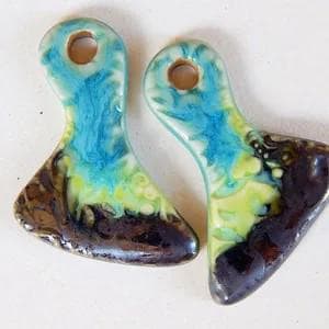May include: Two ceramic pendants with a teal, green, and brown glaze. The pendants are shaped like a teardrop with a hole at the top for hanging.