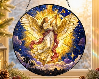 Puede incluir: Un atrapasueños circular de vidrieras que muestra a un ángel con grandes alas doradas tocando una trompeta. El ángel viste una túnica blanca con una faja roja sobre un fondo de sol amarillo brillante, cielo azul estrellado y nubes púrpuras.