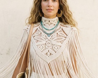 May include: A cream-colored macrame top with fringe detailing. The top is paired with a white skirt and a woven straw bag. The model is wearing turquoise necklaces and gold bracelets. The overall aesthetic is bohemian.