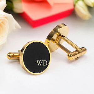 May include: Gold cufflinks with black enamel and the initials "WD" engraved on the front.
