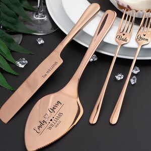 Puede incluir: Juego de cuchillo y servidor para pastel de boda en oro rosa con el texto "Emely & Garry Williams 08.08.22" y dos tenedores en oro rosa con el texto "Bride" y "Groom".