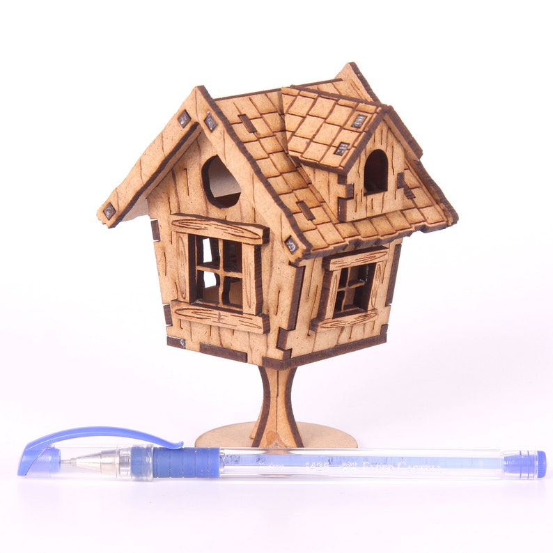 May include: A wooden model of a small house with a gabled roof and windows. The house is on a wooden base and is about 6 inches tall.