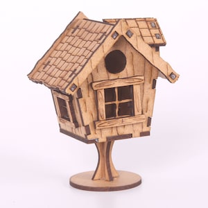 May include: A wooden birdhouse with a shingled roof, a small window, and a round opening. The birdhouse is perched on a wooden stand with a circular base.