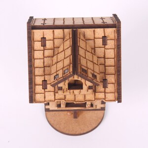 May include: A wooden model of a small house with a gabled roof and a brick facade. The model is detailed with windows and a door. The house is sitting on a round base.
