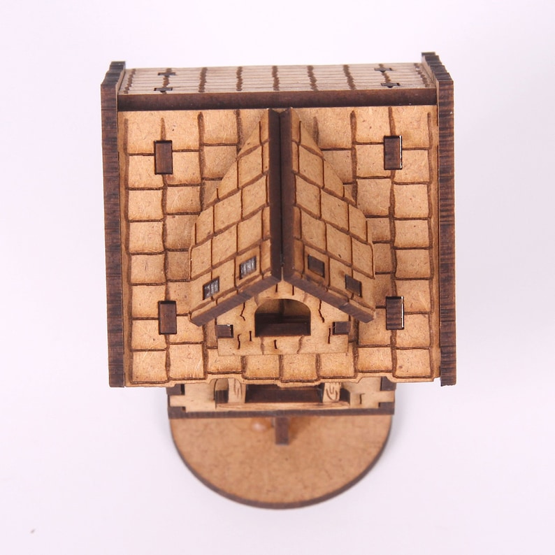 May include: A wooden model of a small house with a gabled roof and a brick facade. The model is detailed with windows and a door. The house is sitting on a round base.