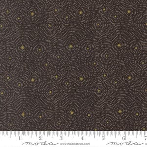 May include: Dark brown fabric with a repeating pattern of gold starbursts. Each starburst has a central gold dot with radiating lines. The fabric has a ruler along the bottom edge with the word "moda" printed on it.