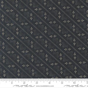 May include: Dark navy fabric with a repeating pattern of tan floral and dotted designs. The pattern is arranged diagonally across the fabric. A ruler is at the bottom of the image, with measurements in inches.
