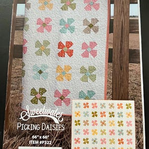 May include: A light gray quilt with colorful flower patterns, displayed on a wooden fence. The quilt measures 66 inches by 66 inches. The image also includes a smaller quilt with the same flower design and the text "Sweetwater Picking Daisies".