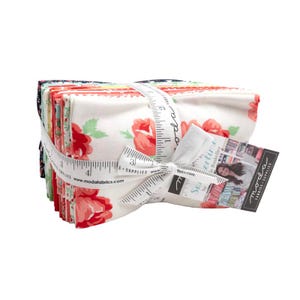 May include: A stack of fabric squares with a floral print in shades of red, white, and green. The fabric is tied together with a white ribbon and a measuring tape. The fabric is labeled "Summertime" by Sue Roskelley.