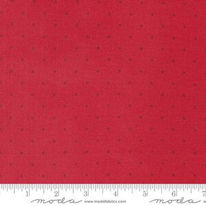 May include: Red fabric with a small, dark gray polka dot pattern. The fabric is shown with a ruler for scale. The ruler has the word "moda" printed on it.