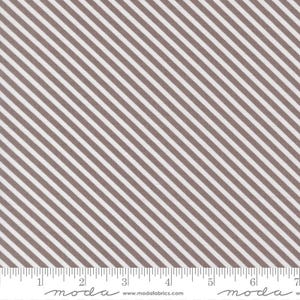 May include: Fabric with a diagonal stripe pattern in brown and white. The stripes are evenly spaced and run across the fabric. A ruler is at the bottom of the fabric, with the word "moda" printed on it.