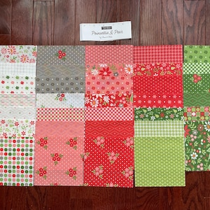 May include: A collection of fabric squares in various patterns and colors, including red, green, and white. Floral, polka dot, and geometric designs are visible. The text "Poinsettia & Pear" is on a small white label.