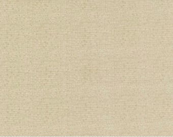 May include: A close-up of a beige fabric with a subtle textured pattern. The fabric is a solid color with a slight sheen. The fabric is measured in inches with a ruler.