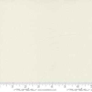 May include: Cream-colored fabric with a subtle woven texture. The fabric is a solid, neutral color, suitable for various sewing and crafting projects. A ruler with inch markings is visible along the bottom edge.