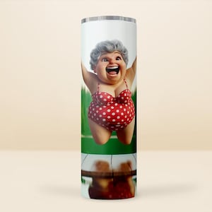 Op de afbeelding: Een witte tumbler met een kleurrijk beeld van een vrouw in een rood-wit geblokt badpak die in een zwembad springt.