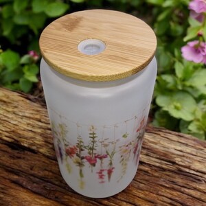 May include: A frosted glass diffuser bottle with a bamboo lid and a floral print. The bottle has a small hole in the lid for mist to escape.