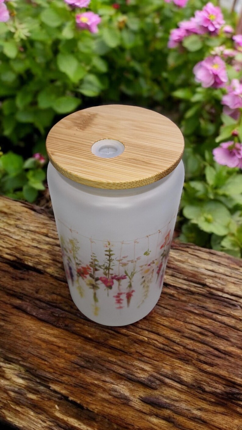 May include: A frosted glass diffuser bottle with a bamboo lid and a floral print. The bottle has a small hole in the lid for mist to escape.
