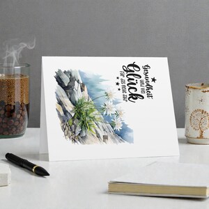 May include: A white greeting card with a watercolor illustration of a mountain scene with white flowers. The card has German text that reads "Gesundheit und viel Gl&uuml;ck f&uuml;r das neue Jahr."