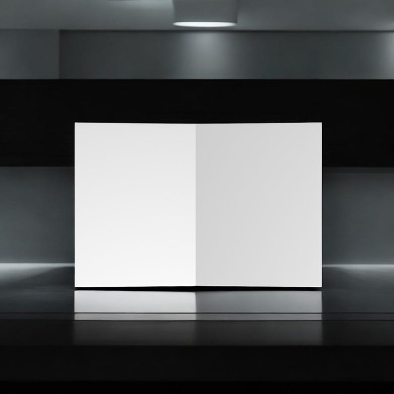 May include: A white, blank, folded poster board stands on a black surface. The poster board is illuminated by a light above.