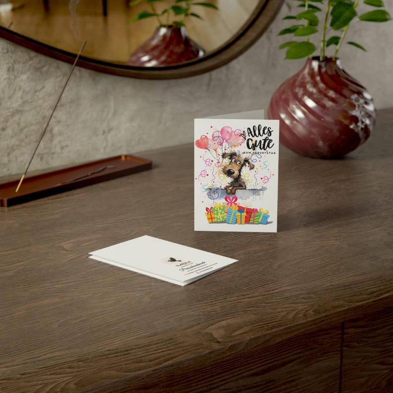 May include: A white card with a cartoon dog peeking over a pile of colorful presents. The card says "Alles Gute zum Geburtstag" in black text.