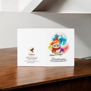 May include: A watercolor illustration of an owl wearing a red Santa hat and a white scarf, perched on a branch in front of a colorful, abstract background. The text "Wunderwolle Weihnachten" is written below the owl.