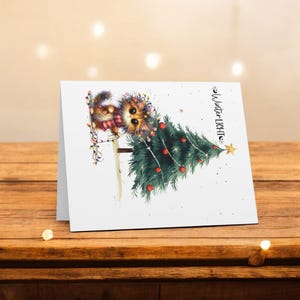 May include: A white Christmas card with a cartoon cat decorating a Christmas tree with lights. The text on the card reads "Winter Lights".