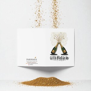 May include: A white greeting card with a gold and green champagne bottle design. The card has the words "Guten Rutsch" and "Parihaus" printed on it. Gold confetti is scattered around the card.
