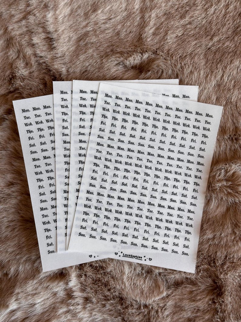 May include: Several white paper sheets with a repeating pattern of days of the week in a grid. The text is in black. The sheets are on a textured, light brown surface. The bottom sheet has the text "LoveSophiee".