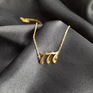 May include: A gold chain necklace with a pendant featuring the number 777 in a stylized font.