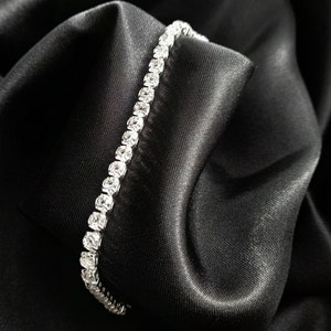 May include: A silver bracelet with a row of clear cubic zirconia stones.