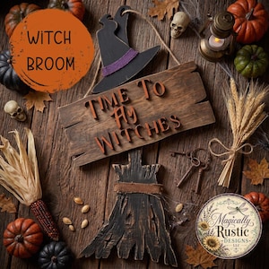 May include: A wooden sign with the text TIME TO FLY WITCHES, featuring a black witch hat with a purple band and a broomstick cutout. The arrangement includes small pumpkins, a skull, a lantern, dried corn, and wheat stalks.