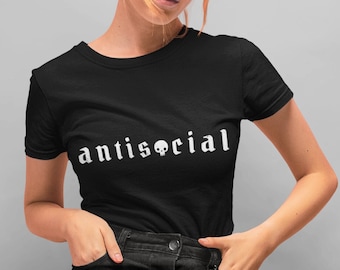 May include: A black t-shirt with the text "antisocial" in white with a skull graphic in place of the "o". The model is wearing a black skirt and has red hair.